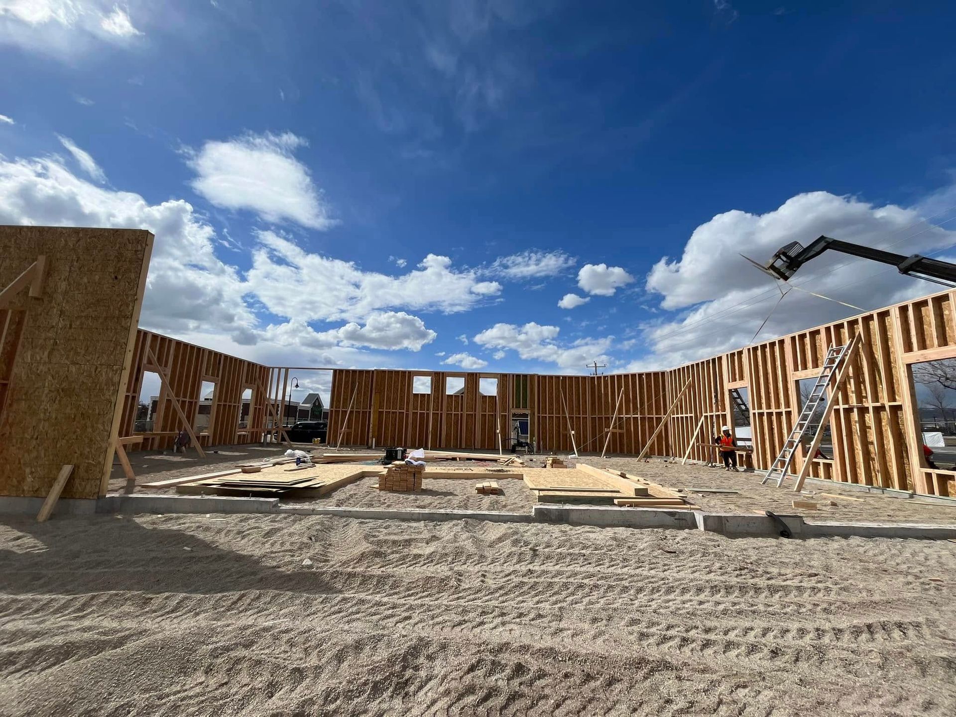 A large building is being built in the middle of a dirt field.