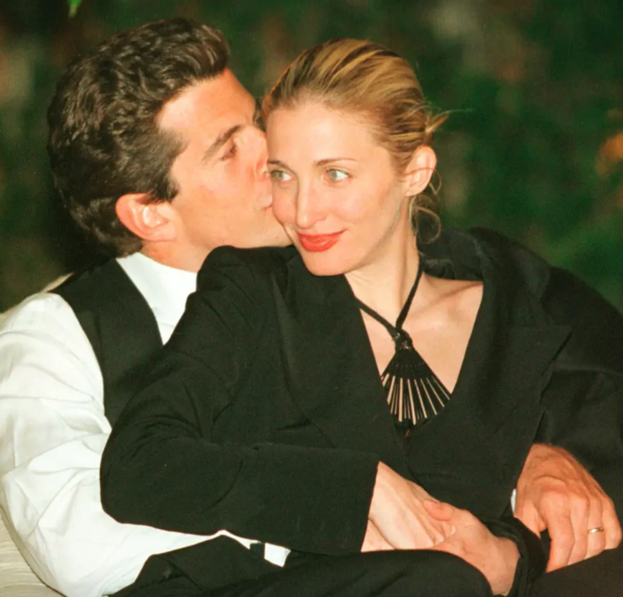 JFK Jr. holding Carolyn Bessette and kissing her on the cheek.