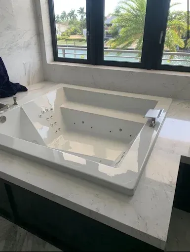 White built-in bathtub with faucet beside a window in a bright bathroom