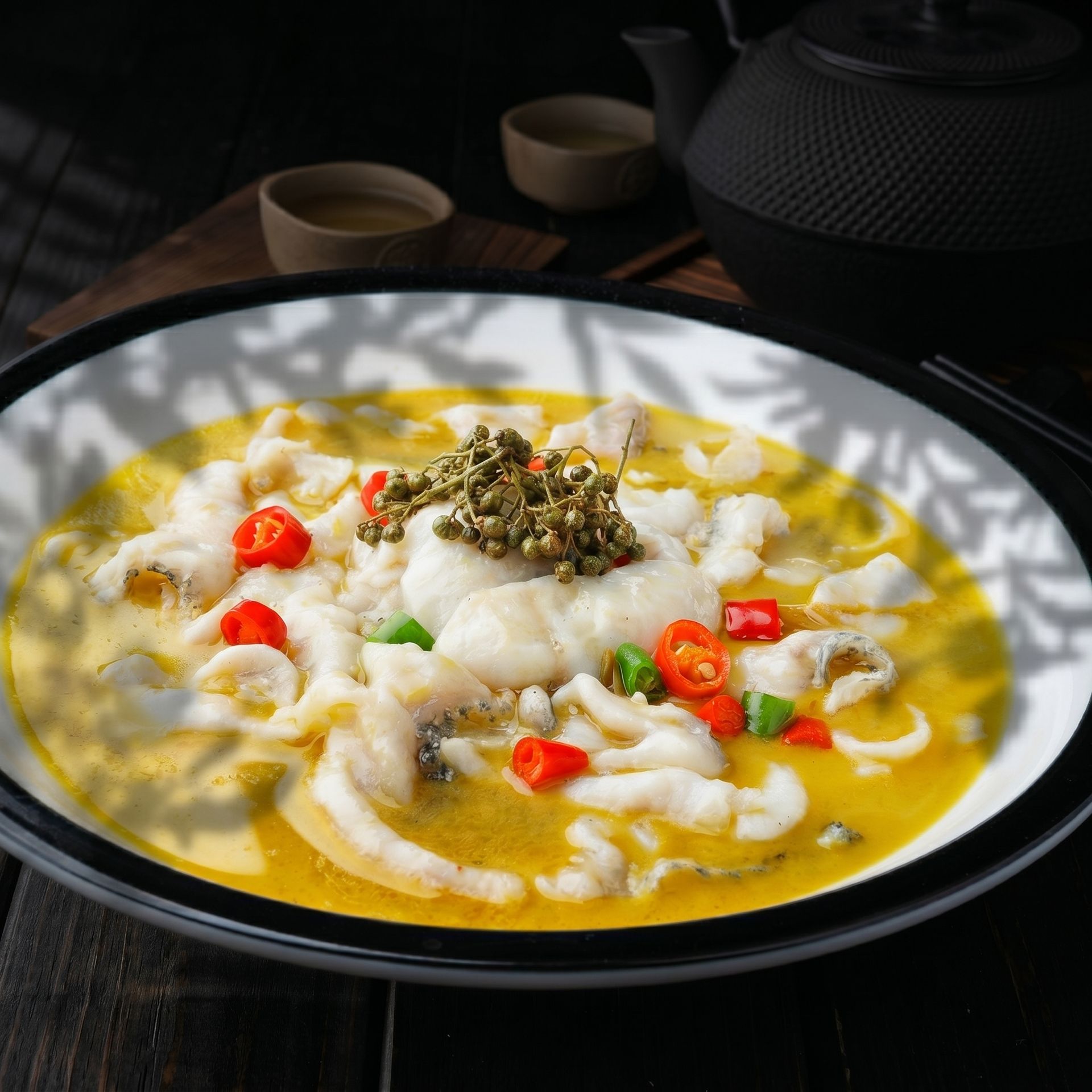 Bowl of noodle soup with chopped red chilies and herb garnish on a dark table