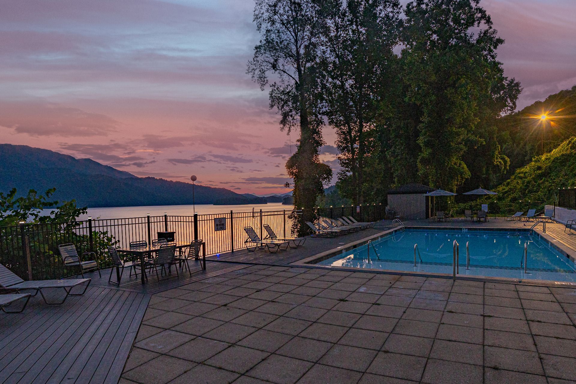 Lakeside swimming pool and patio with lounge chairs at sunset