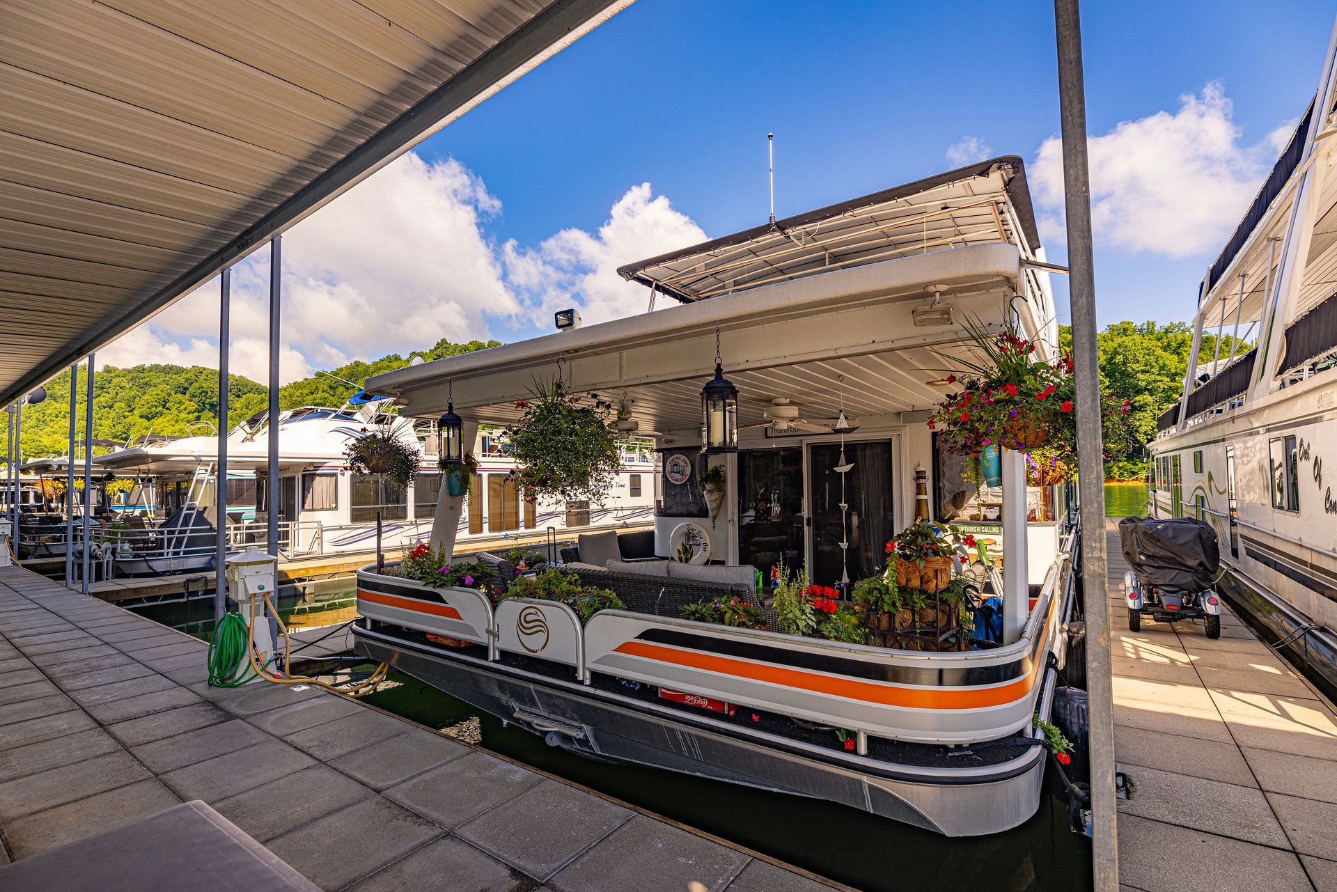 Houseboat with flower planters and lanterns moored at a covered dock