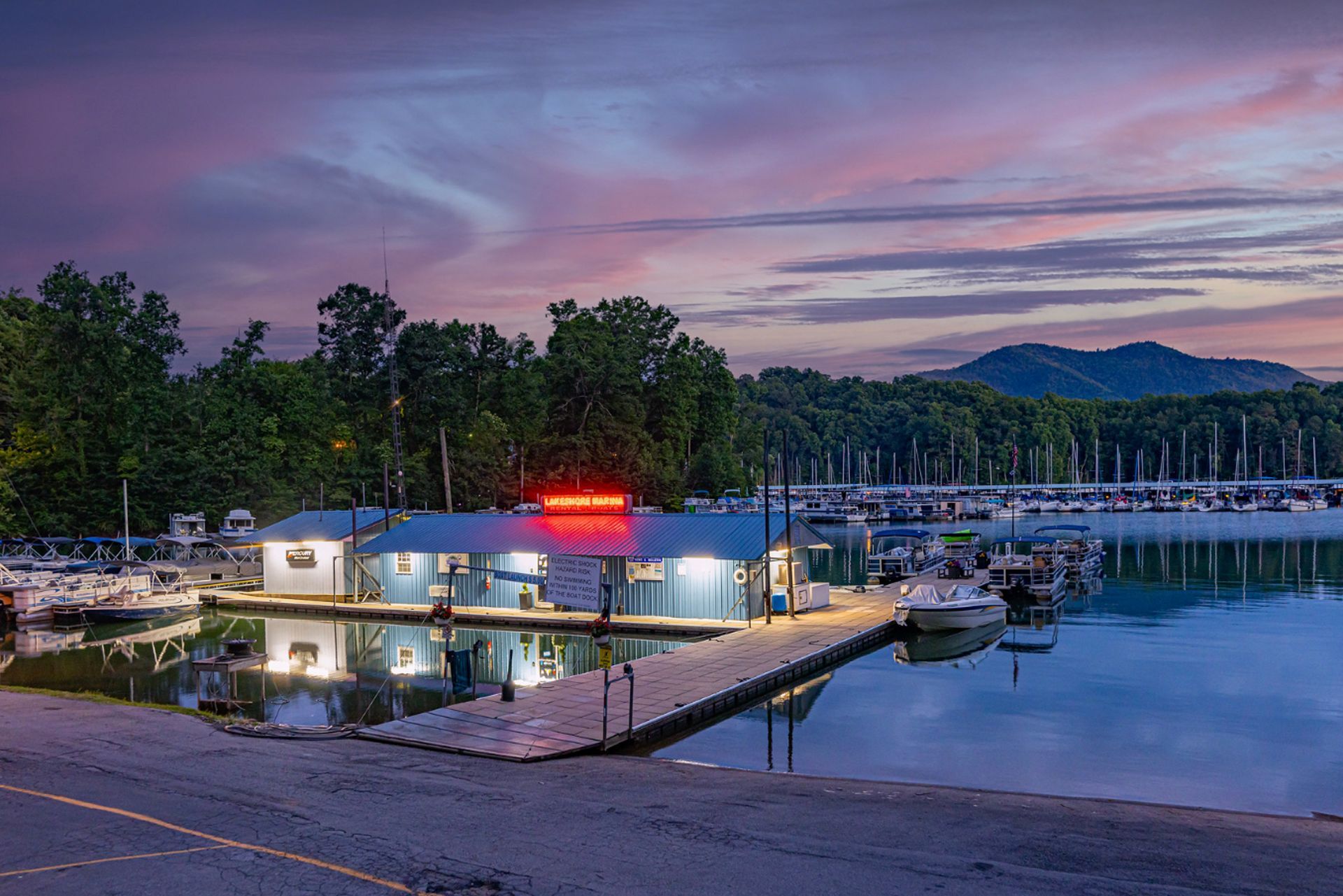 Marina building and docks lit up at dusk under a pink and purple sky