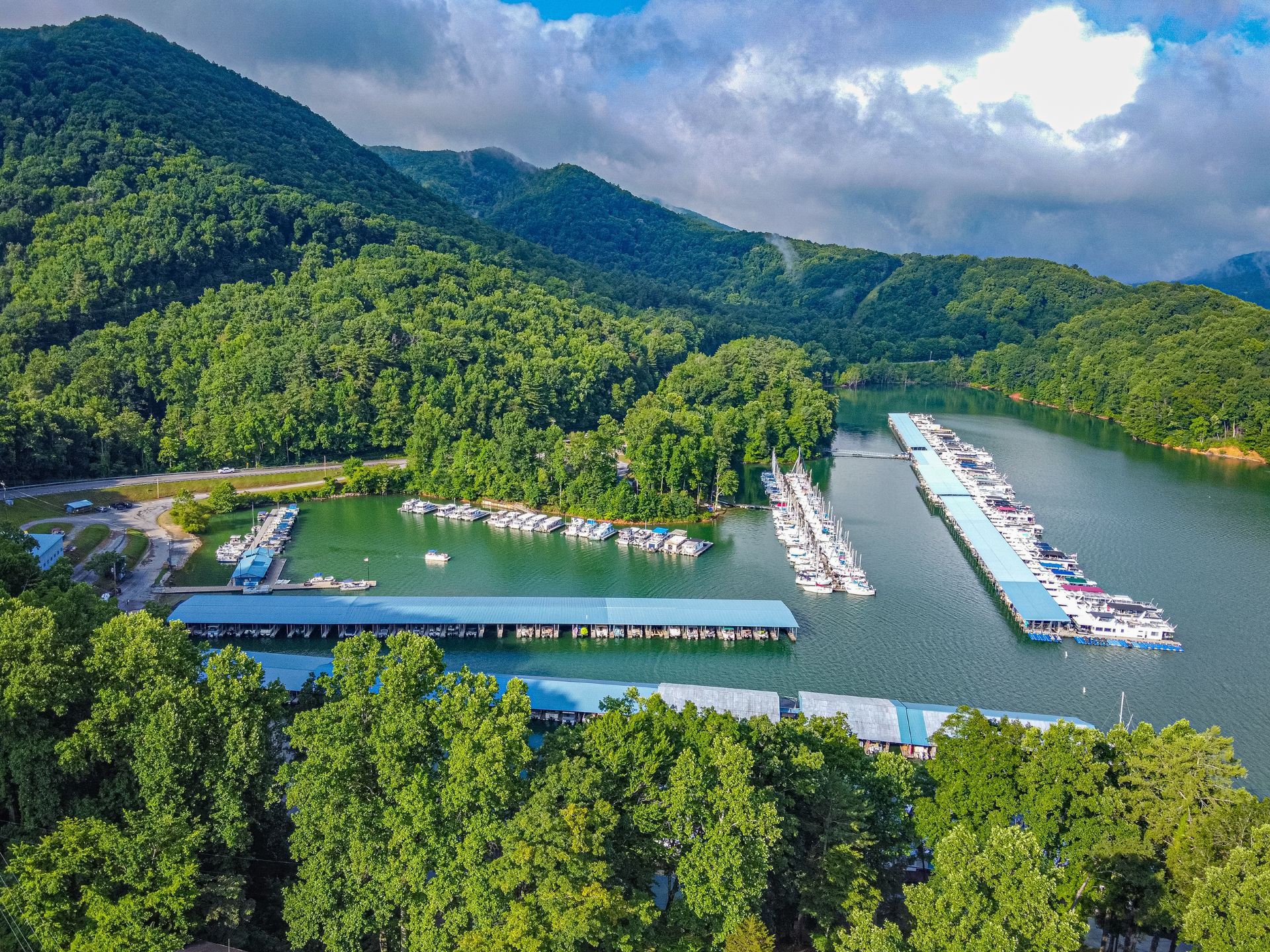 An aerial view of a marina surrounded by trees and mountains.