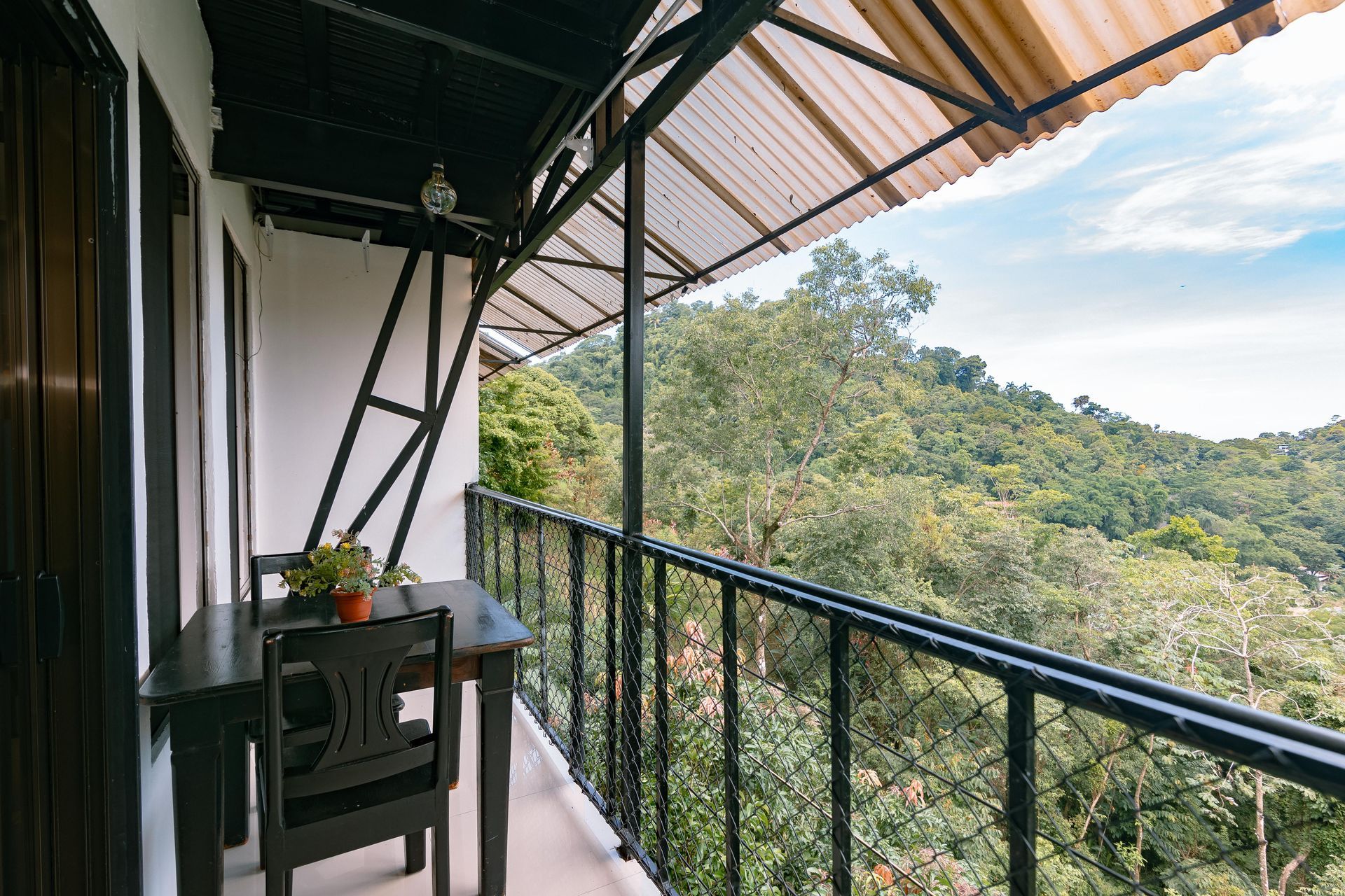 Un balcón con mesa y sillas con vista a un bosque.