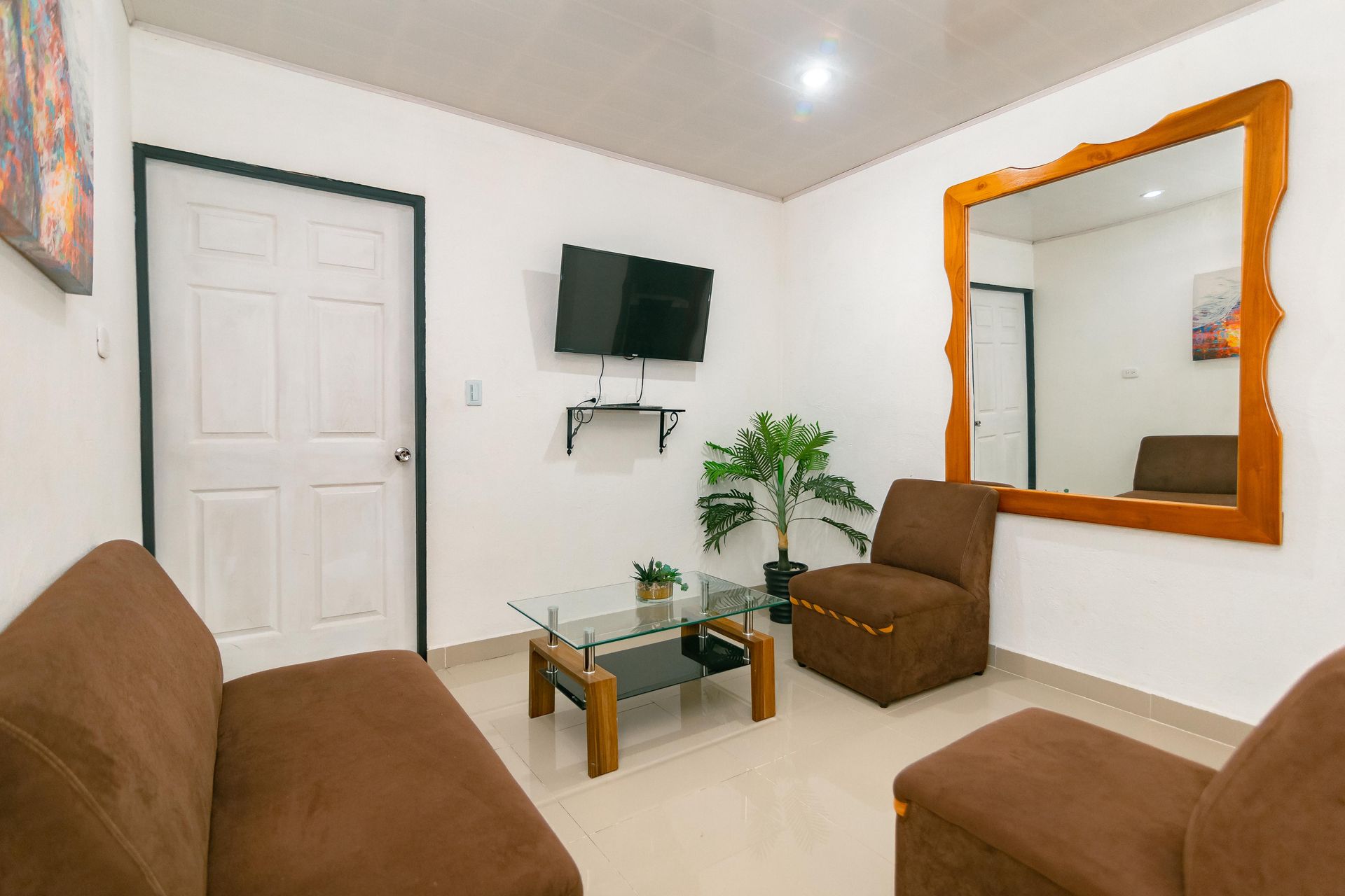 Una sala de estar con sofá, silla, mesa de café y televisión.