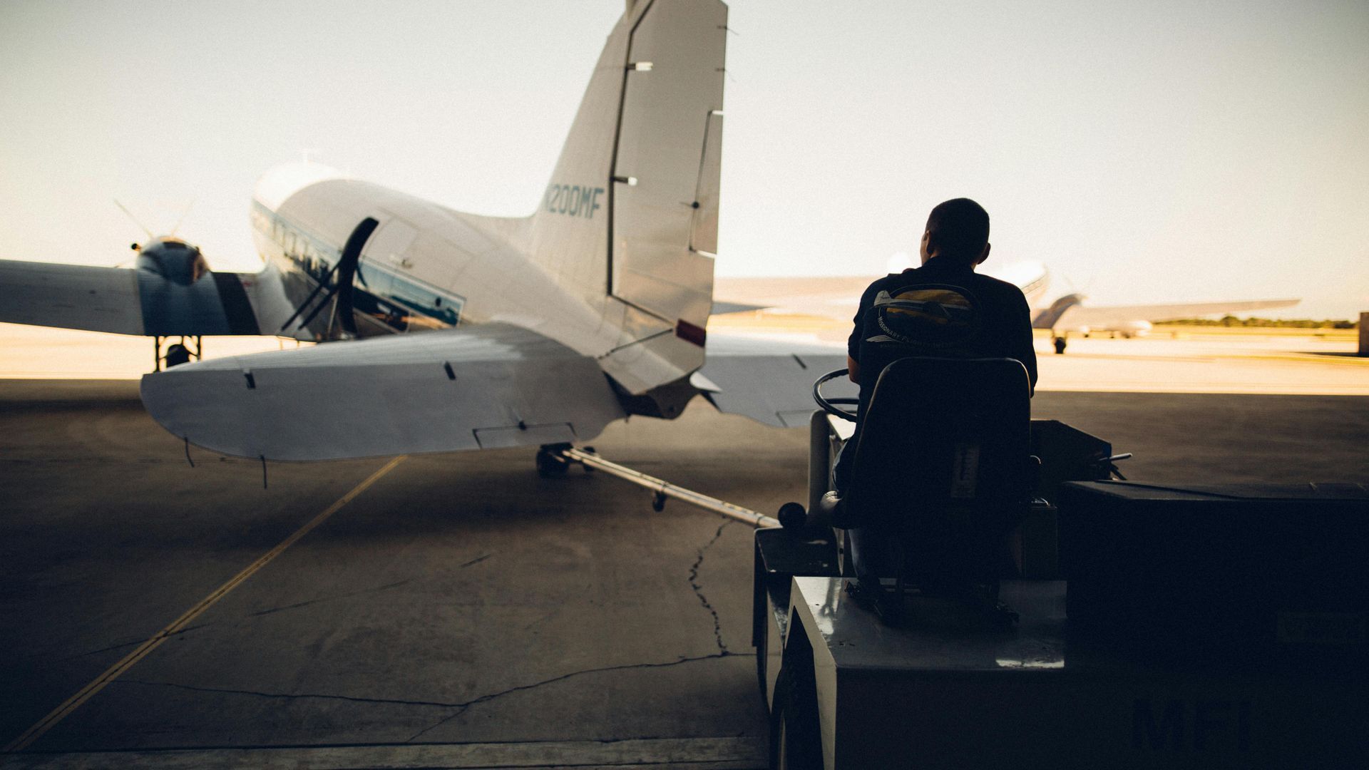 Un hombre está sentado en una grúa al lado de un avión.