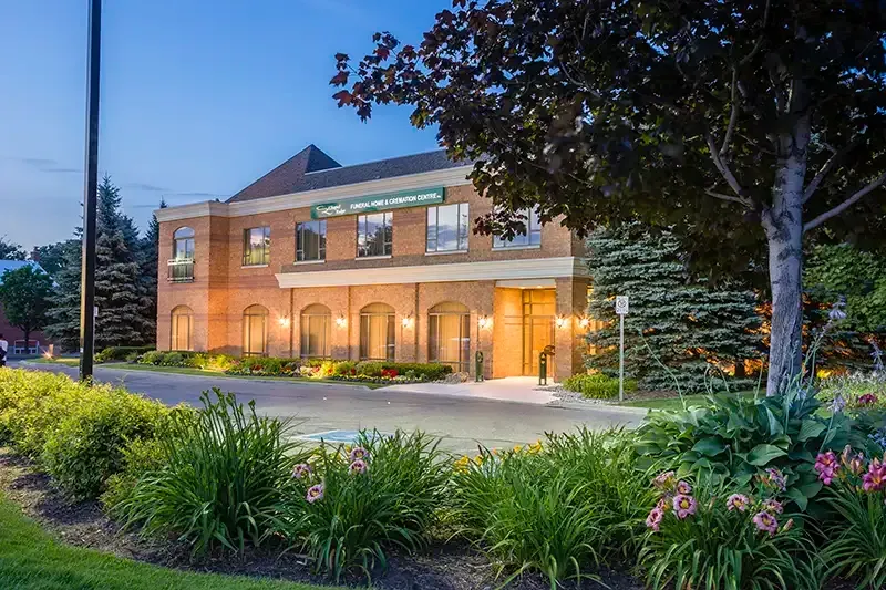 Brick building with arched windows and landscaping, at dusk.