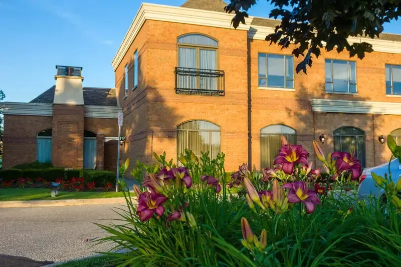 Brick building with flower garden in front.