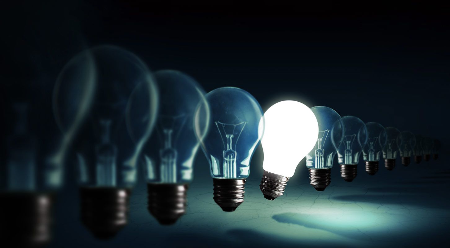 Row of light bulbs, one lit brightly; dark background.