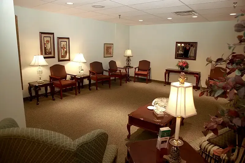 A waiting room with armchairs, lamps, artwork, and a coffee table.