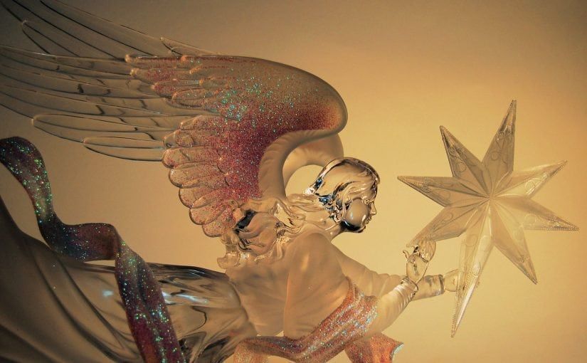 Glass angel with wings holding a star, set against a warm yellow background.