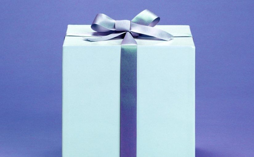 White gift box with a silver ribbon and bow on a purple background.