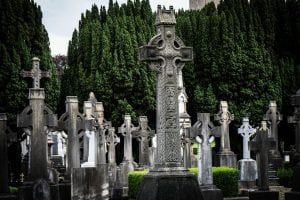 Celtic crosses in a cemetery, gray stone with green trees in the background.
