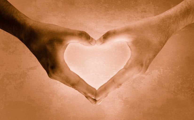 Two hands forming a heart shape with glowing light in the center.