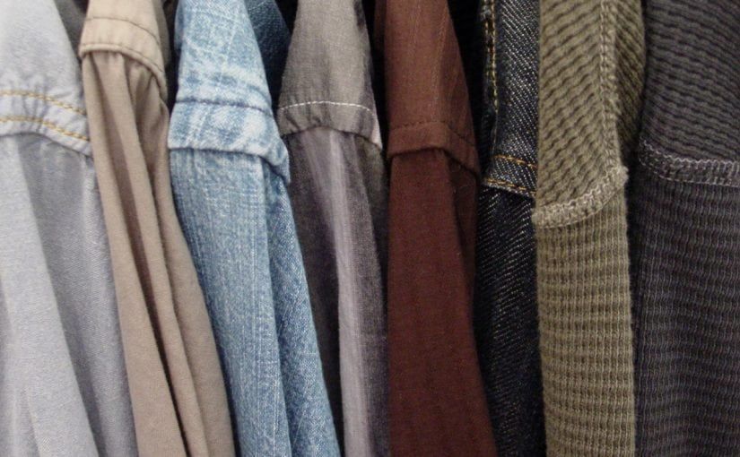 Clothes hanging on a rack; light grey, denim, brown, and textured green shirts.