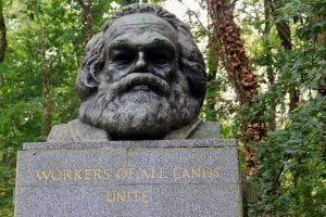 Bust of Karl Marx with a full beard on a pedestal that reads