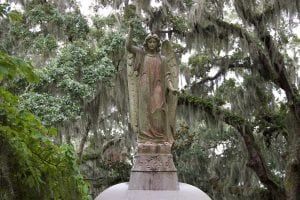 Angel statue in Bonaventure Cemetery, Savannah, Georgia, surrounded by moss-covered trees.