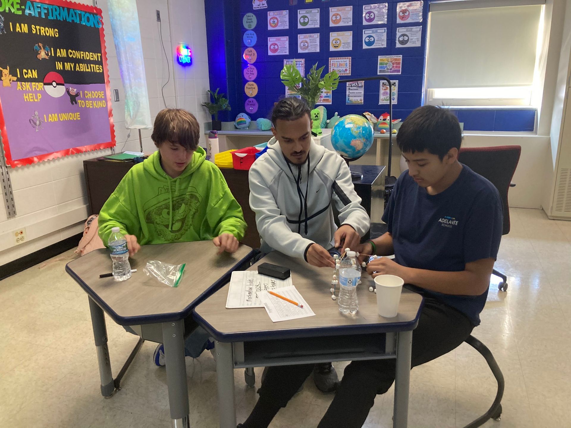Mr. Nance working with two students as they build a spaghetti and marshmallow tower