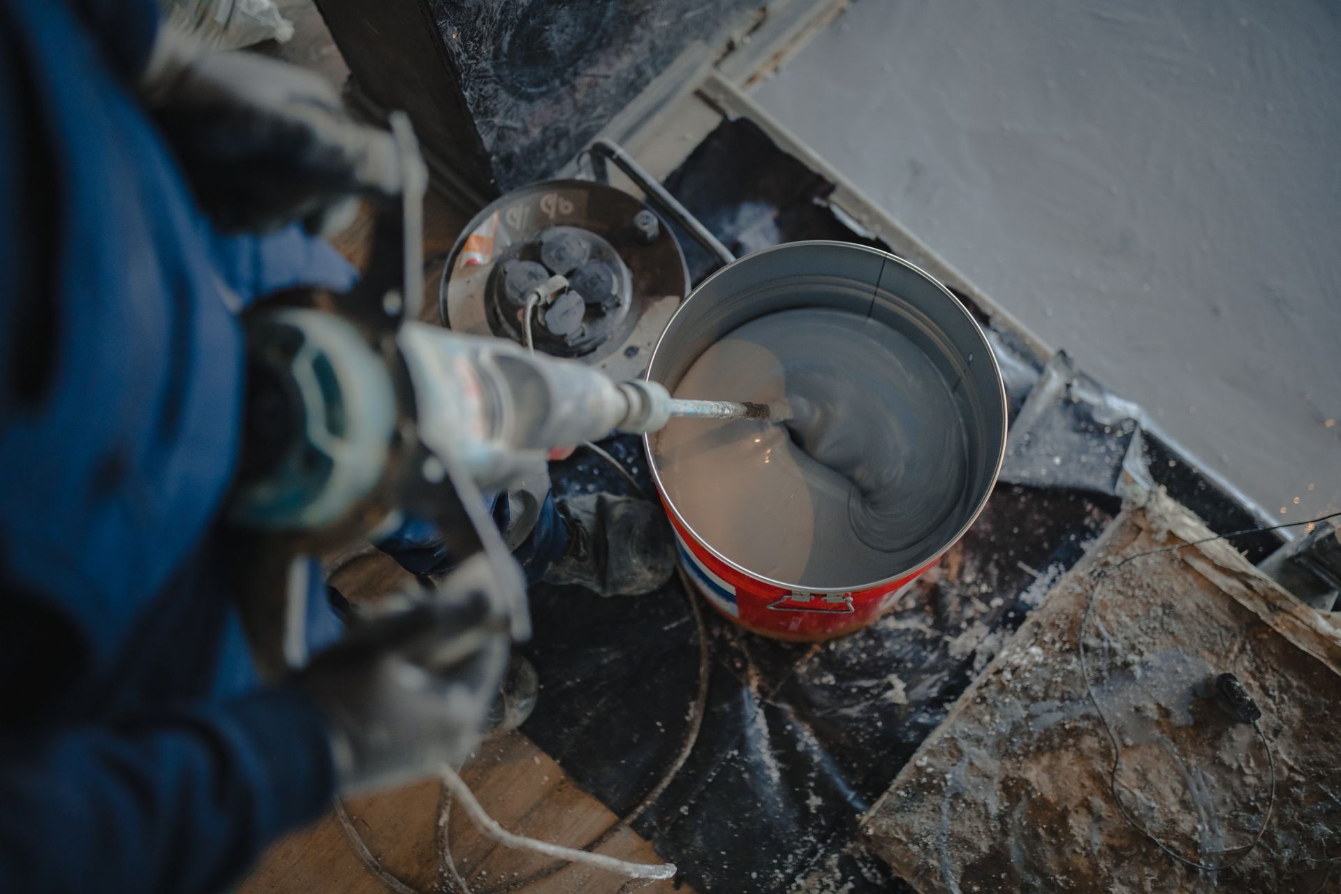 a garage with a gray floor and white walls. Epoxy being mixed.