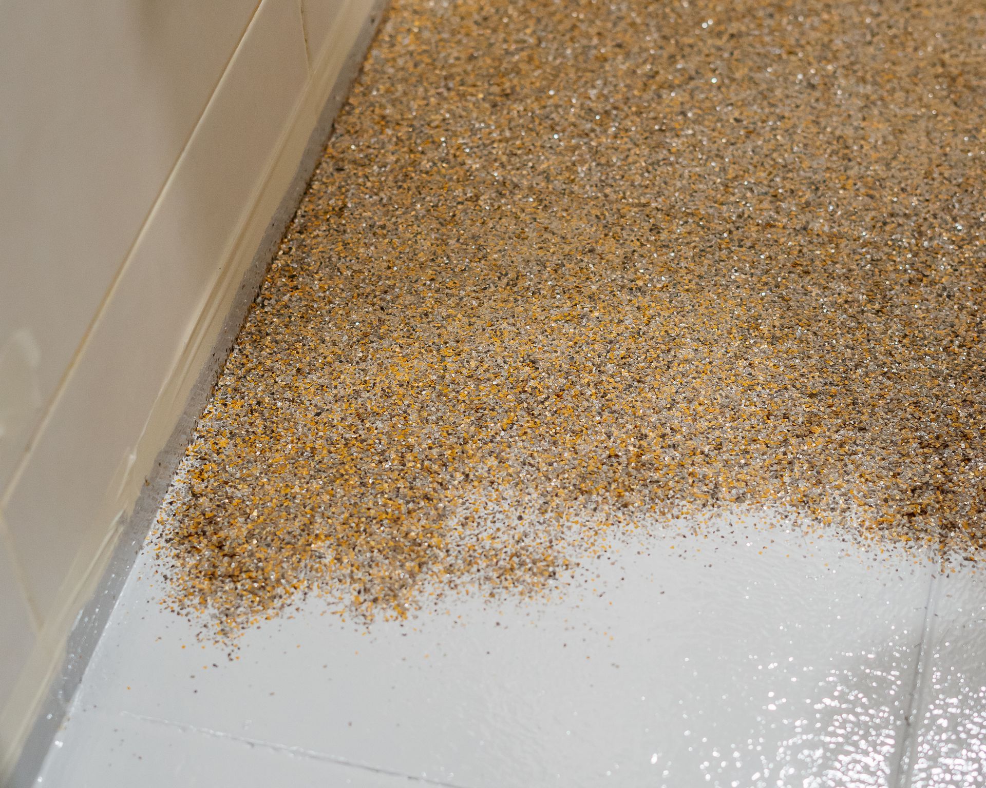 a garage with a gray floor, white walls, and gold color epoxy flake.