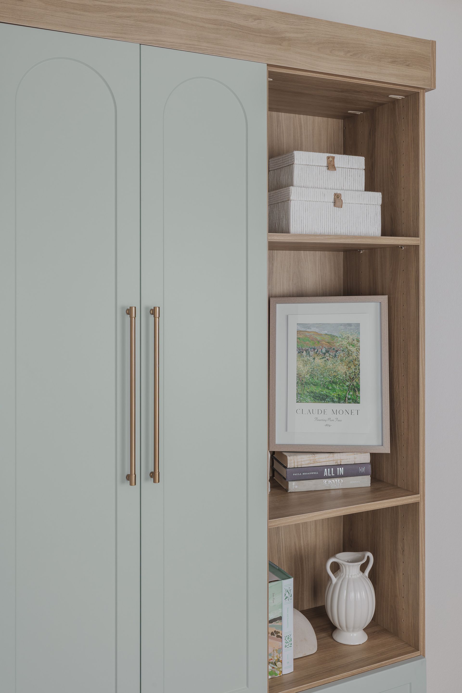 Built-in shelving beside a white cabinet, styled with framed art, books, and decorative vases.