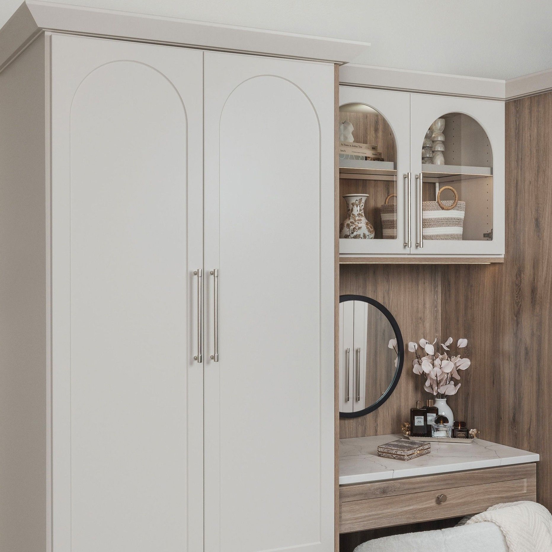 Small dressing area with a white wardrobe, vanity mirror, wood paneling, and decorative shelves.