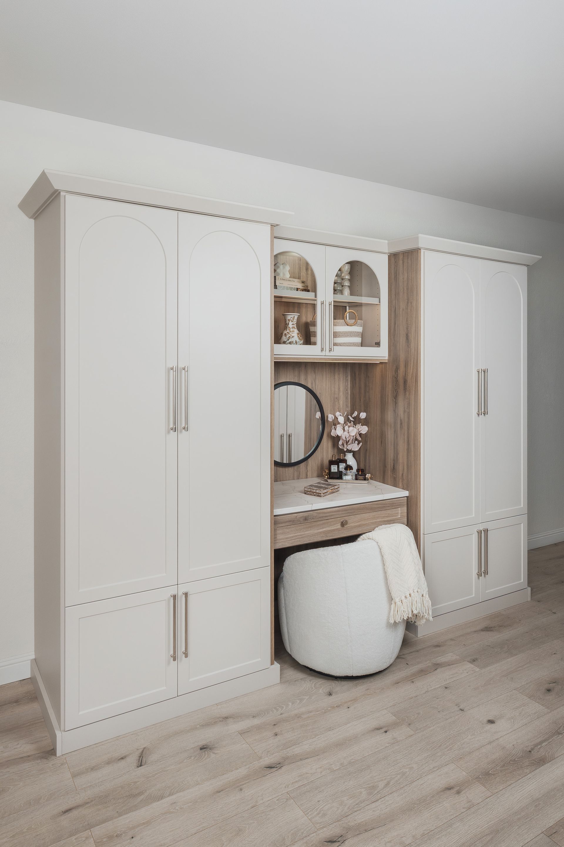 White wardrobe and vanity set with mirror and stool in a light, empty room