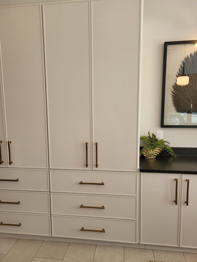 A kitchen with white cabinets and drawers and a picture on the wall