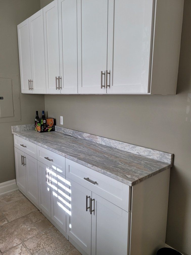 A kitchen with white cabinets and granite counter tops.