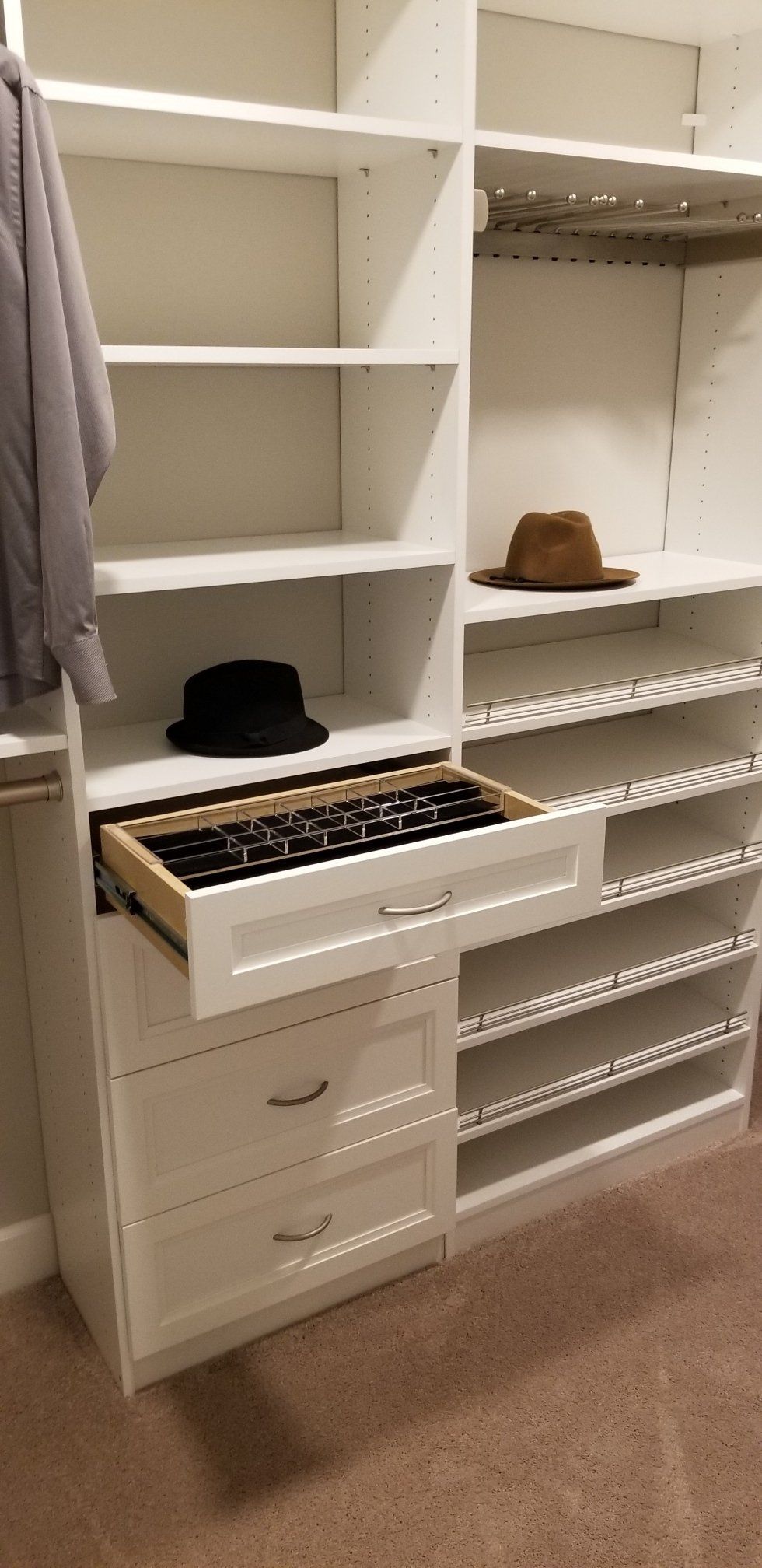 A walk in closet with a drawer open and a hat in it.