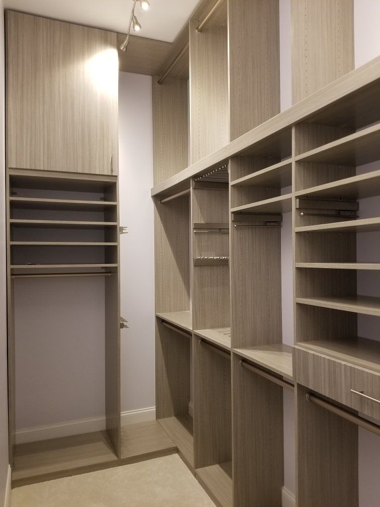 A walk in closet with lots of shelves and cabinets