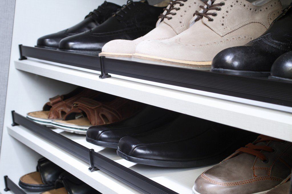 Shoes lined up on white shelves in a closet or shoe rack