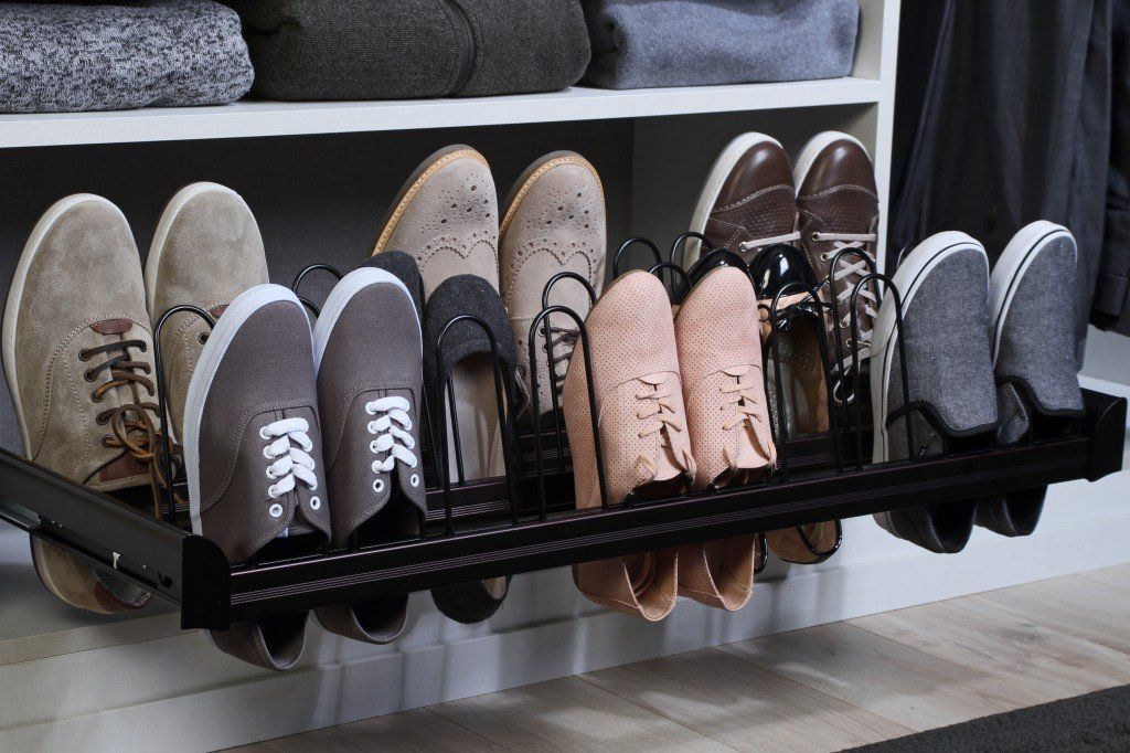 Row of assorted shoes neatly stored on a black hanging rack in a closet