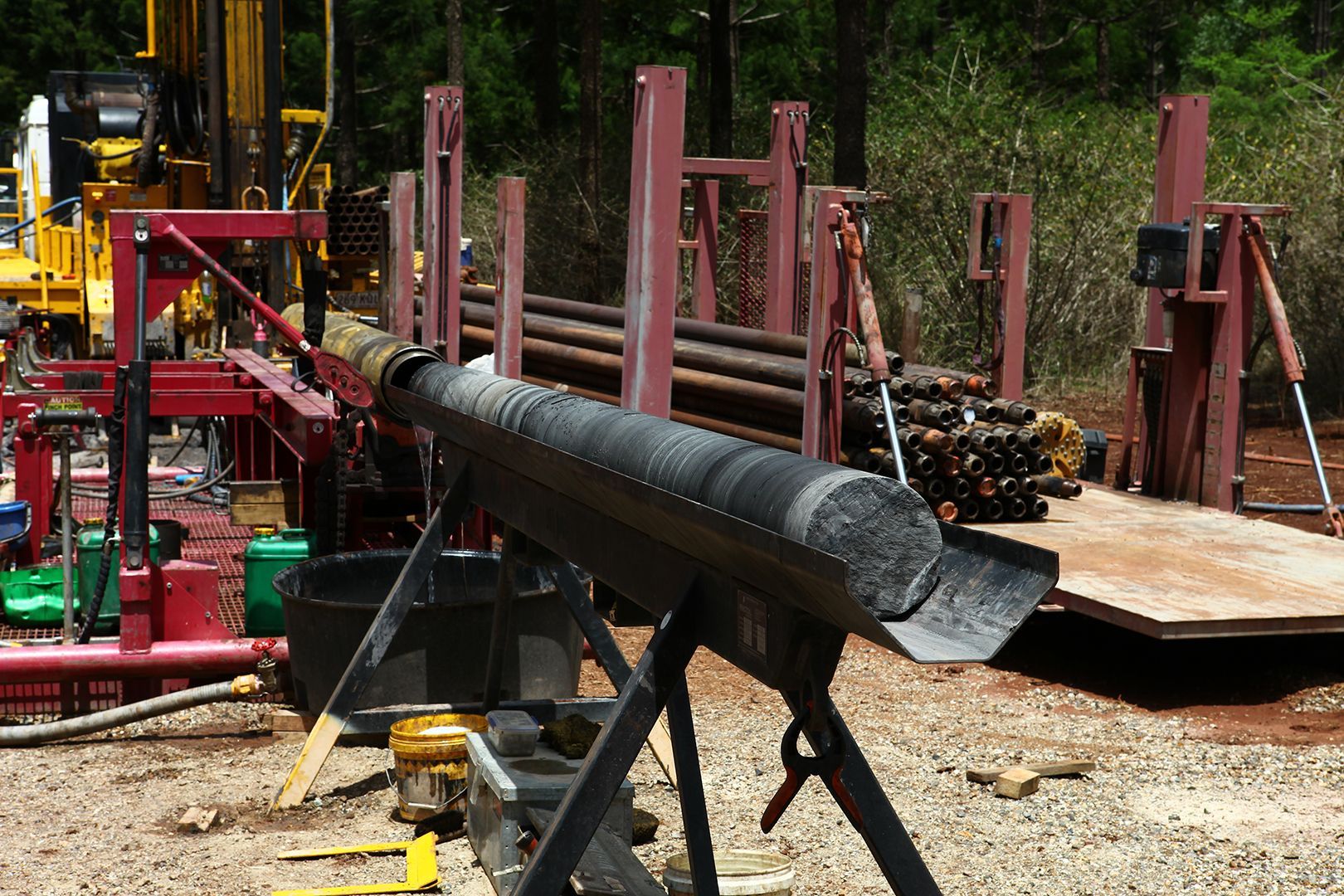 Drilling rig equipment in outdoor setting; pipes are being moved.