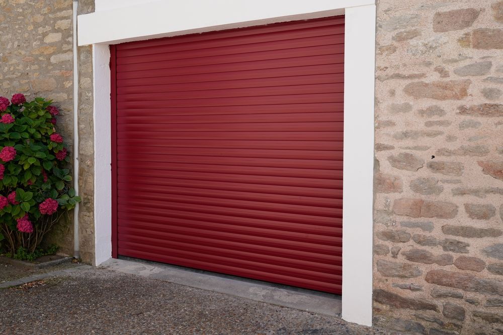 A Red Roller Shutter is Against a Stone Wall — Window Coverings in Cardiff, NSW