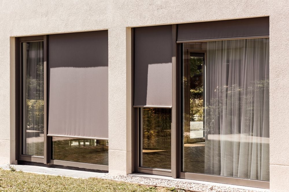 A Sliding Glass Door With a Gray Blind on It — Window Coverings in Cardiff, NSW