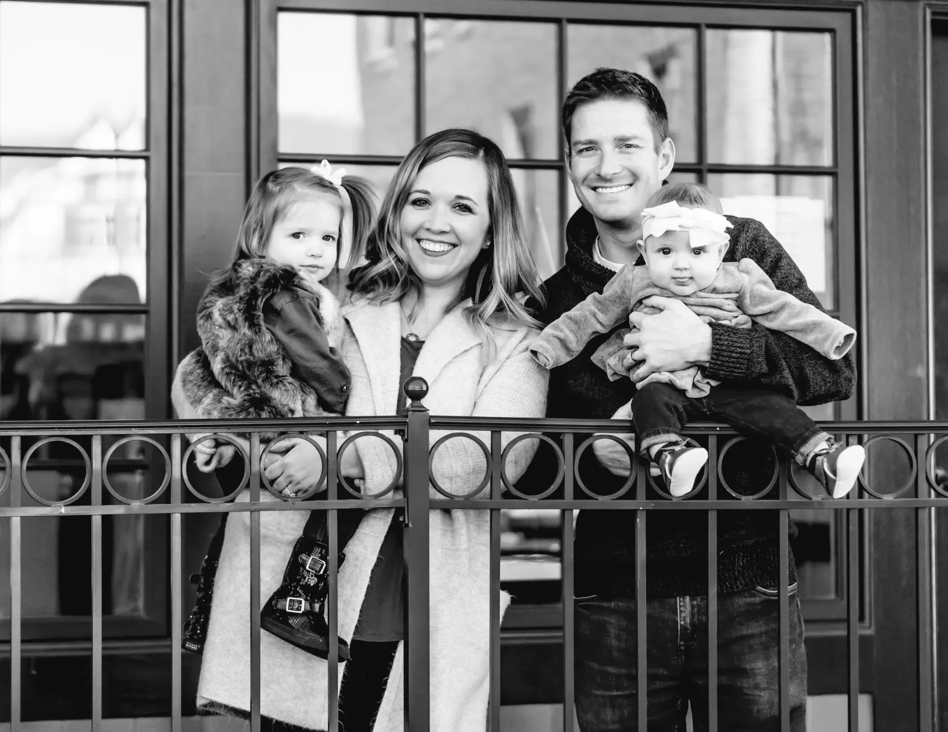 A black and white photo of a family standing on a balcony.