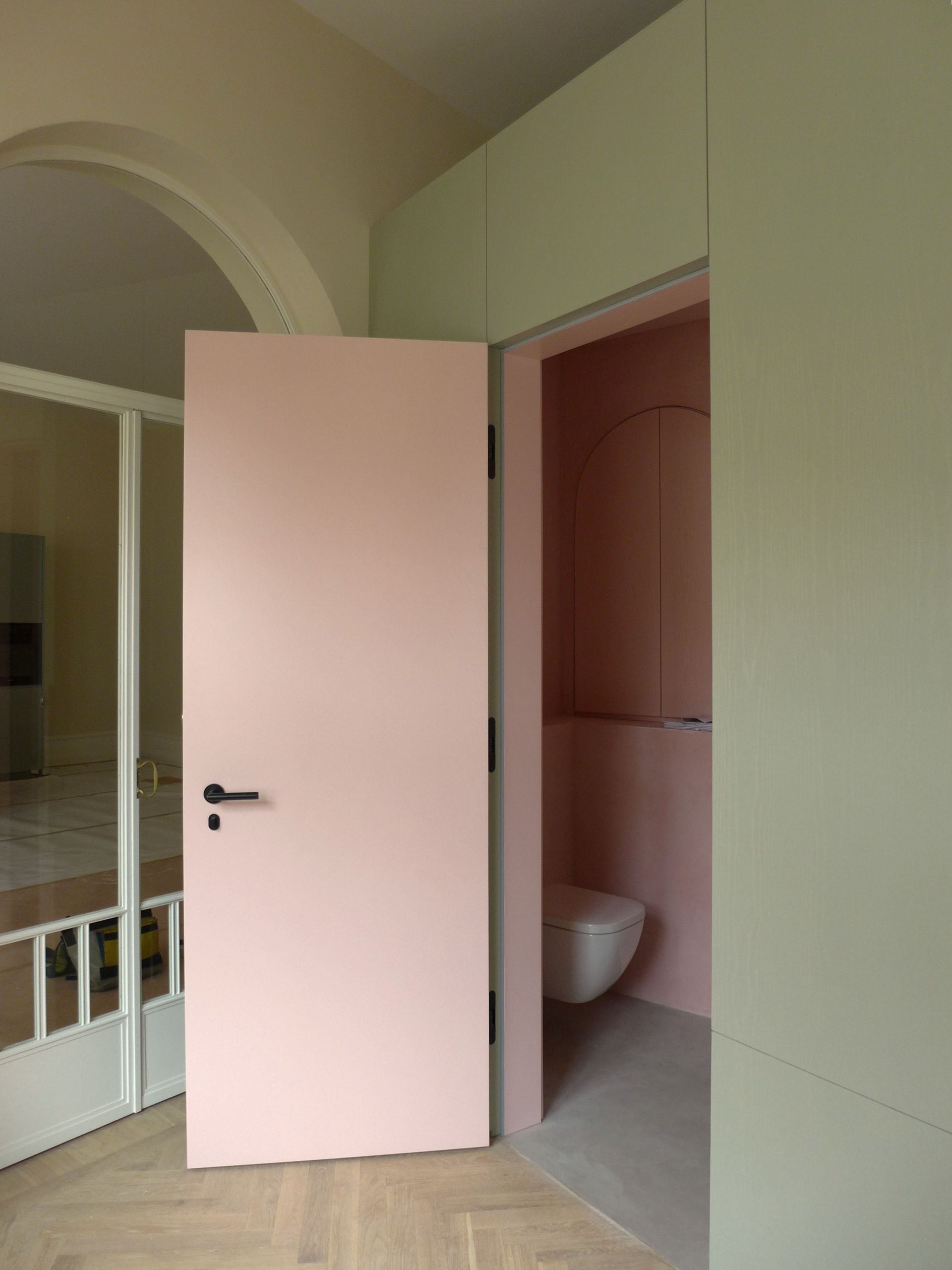 Ein Zimmer mit einer rosa Tür und einer Toilette