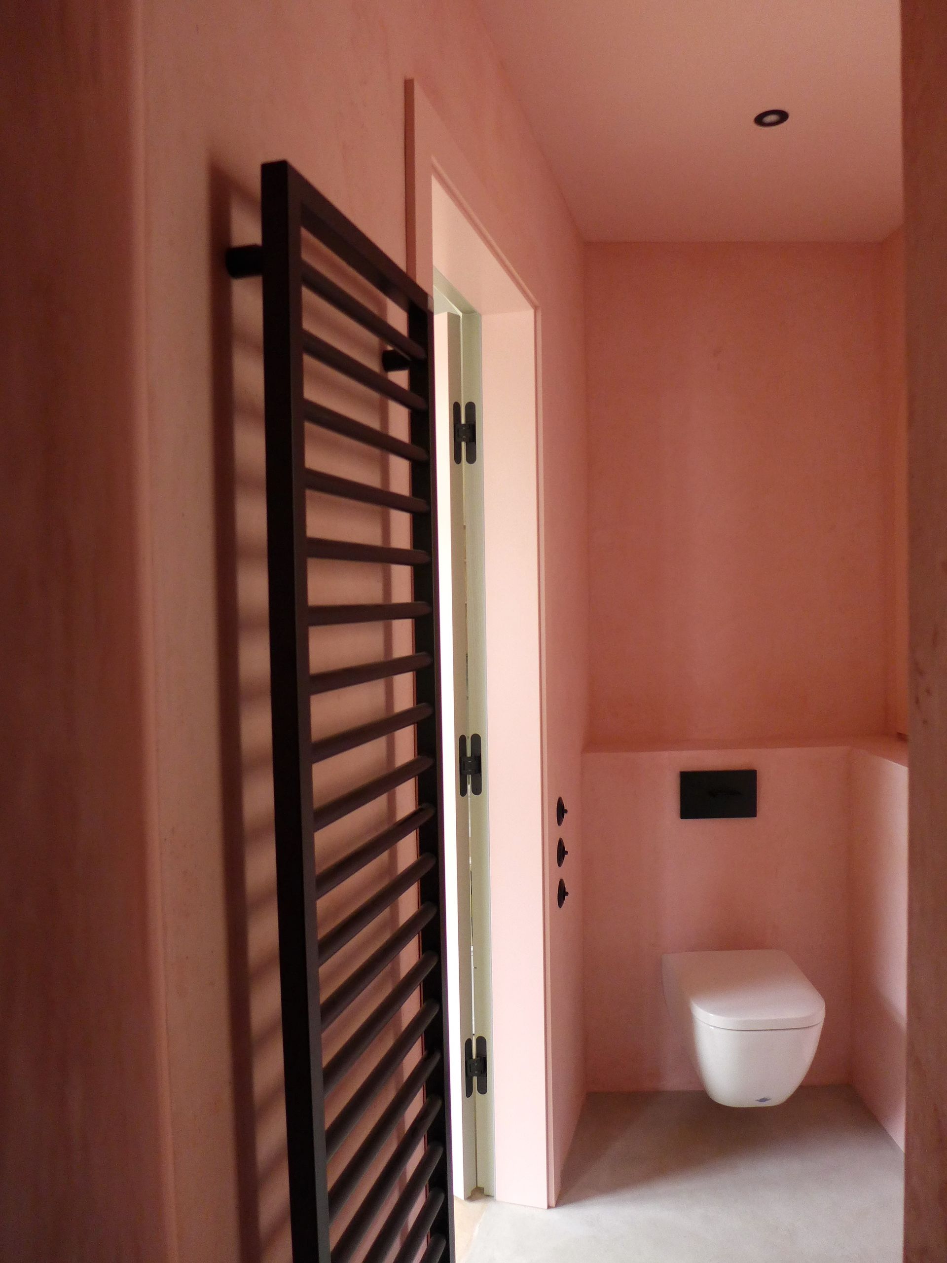 Ein Badezimmer mit rosa Wänden und einer weißen Toilette