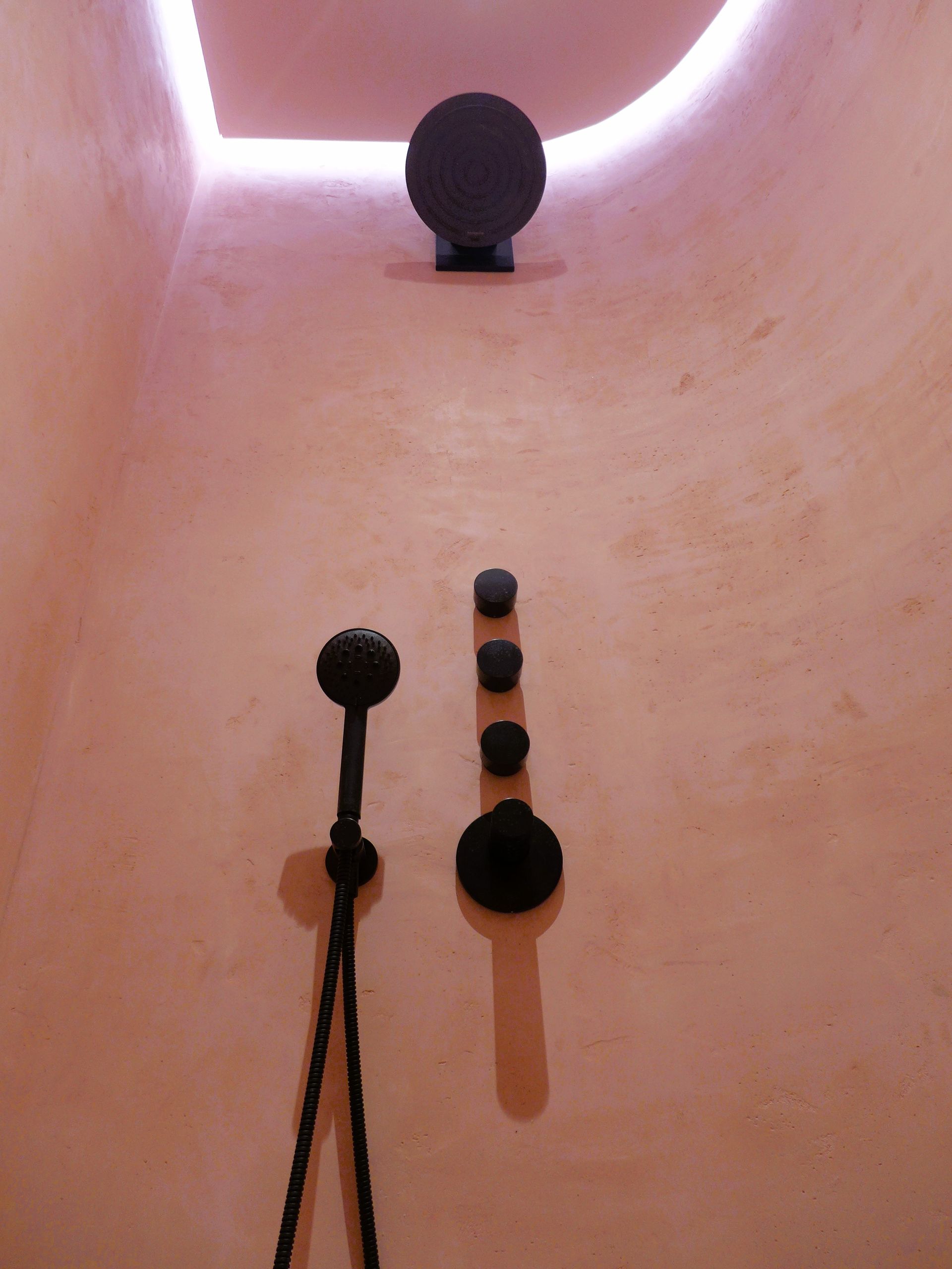Ein Badezimmer mit Duschkopf und Deckenleuchte