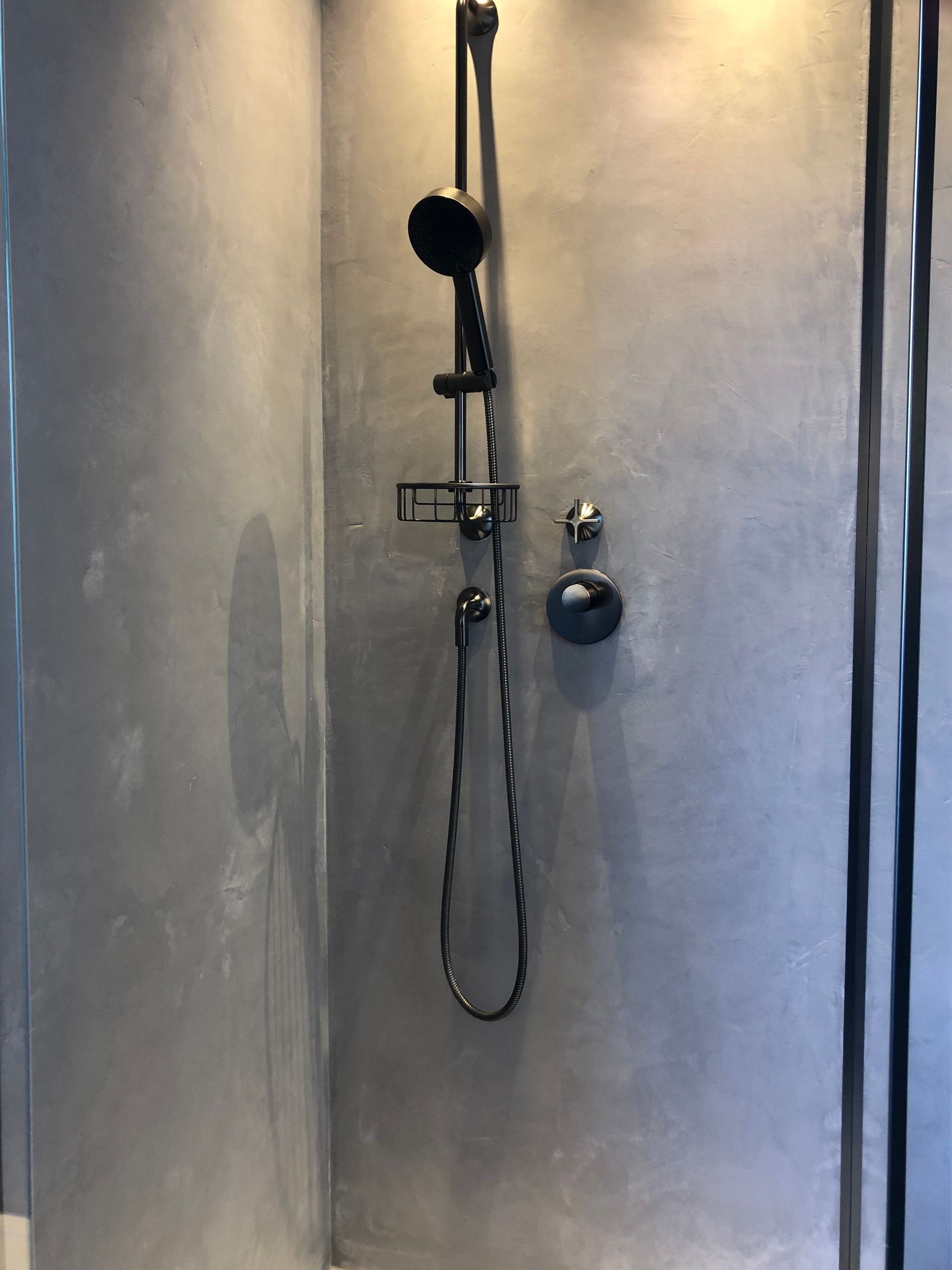 Eine Dusche mit einem schwarzen Duschkopf, der an der Wand hängt