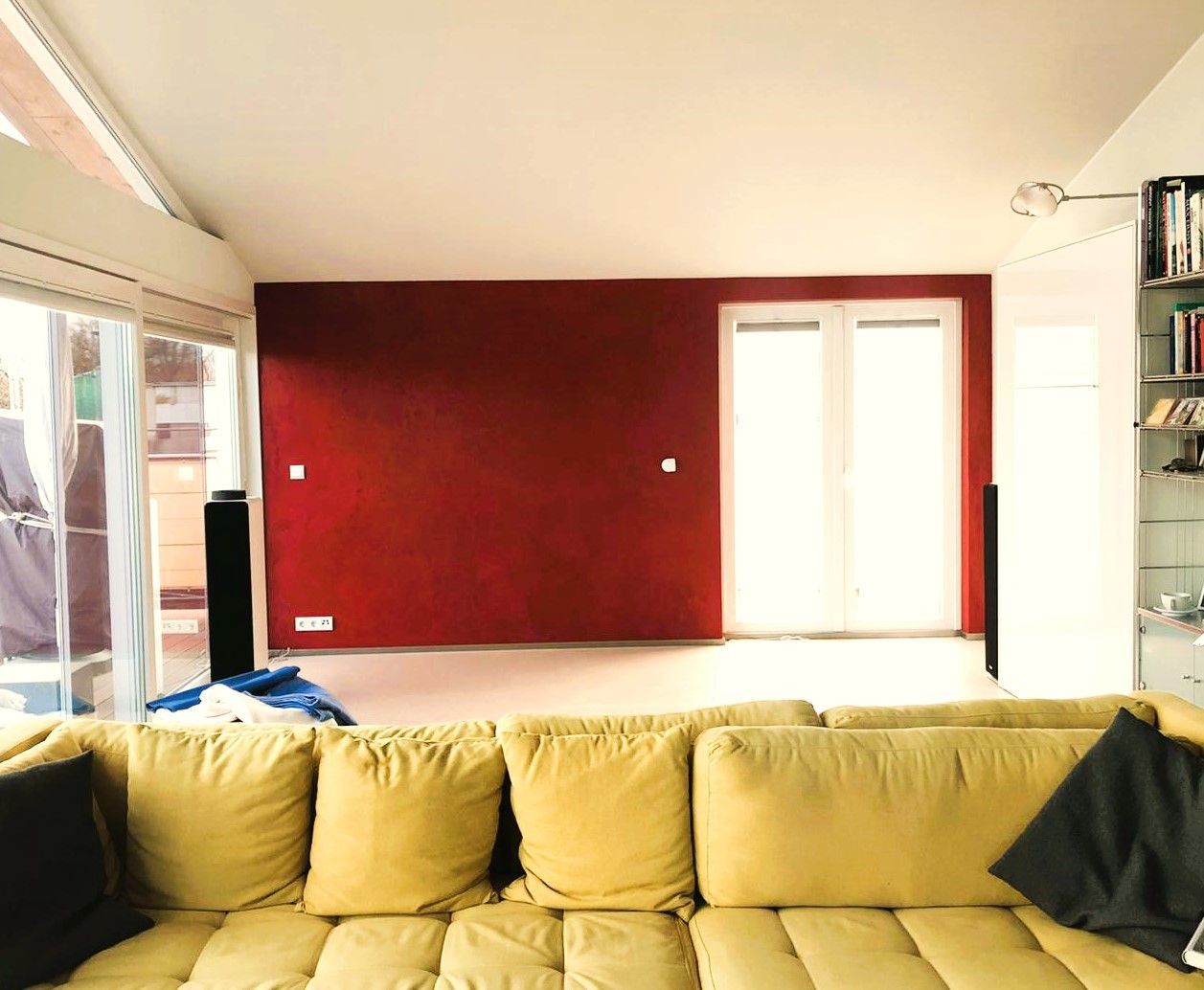 Ein Wohnzimmer mit einer gelben Couch und einer roten Wand