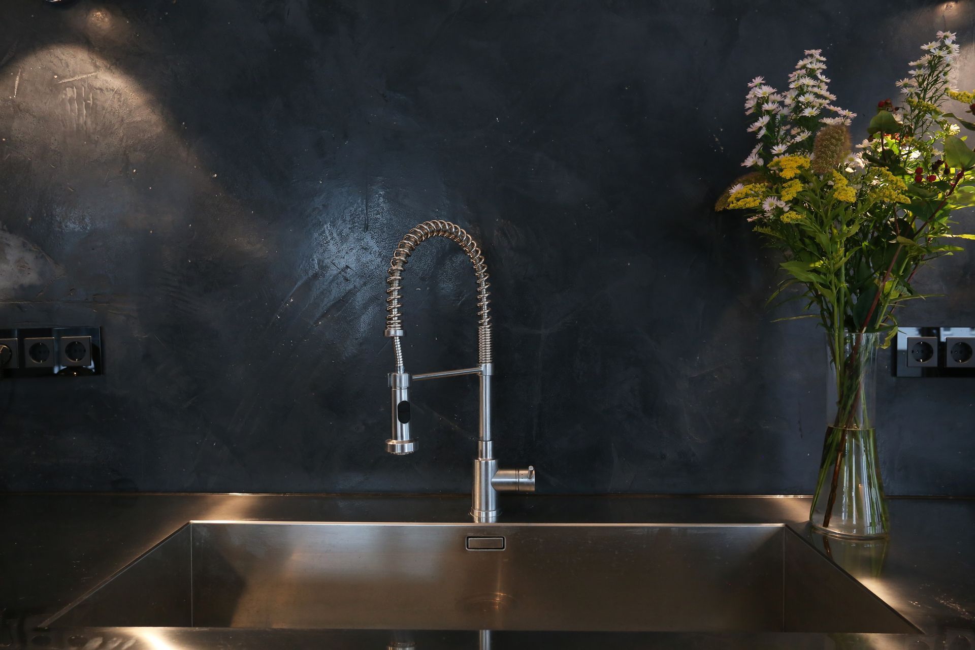 Eine Küchenspüle mit Wasserhahn und einer Vase mit Blumen