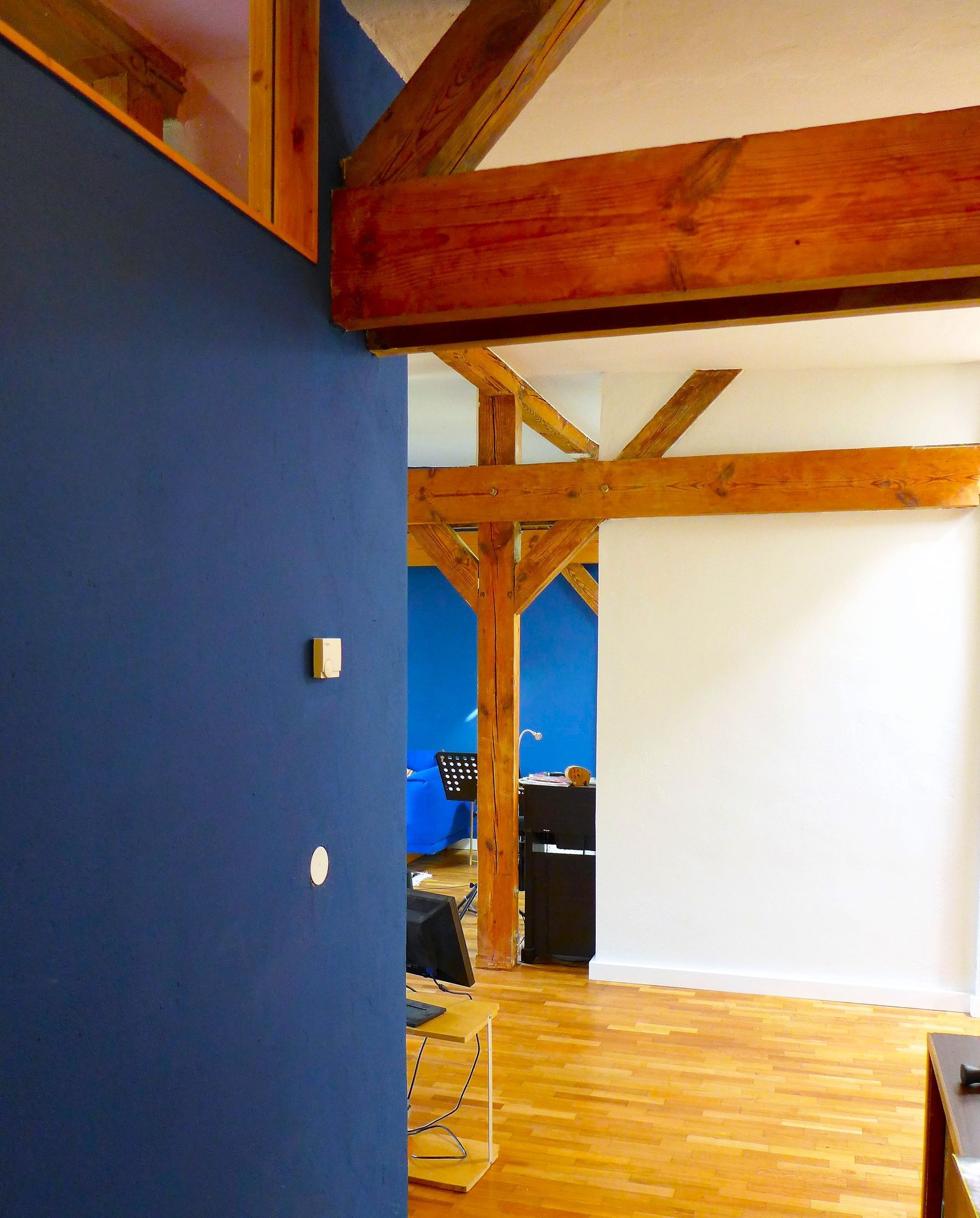Ein Raum mit einer blauen Wand und Holzbalken