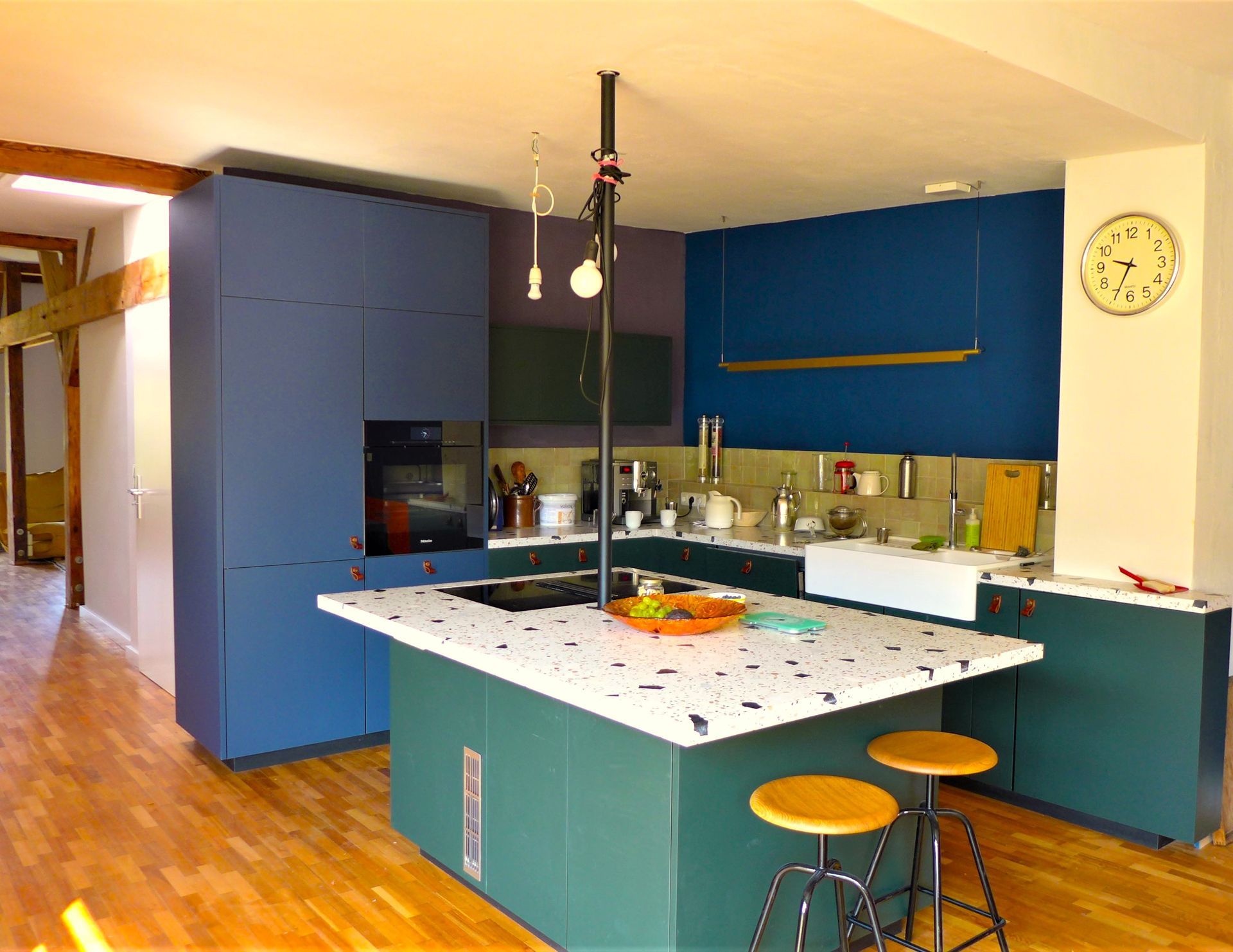 Eine Küche mit blauen Schränken und einer Uhr an der Wand