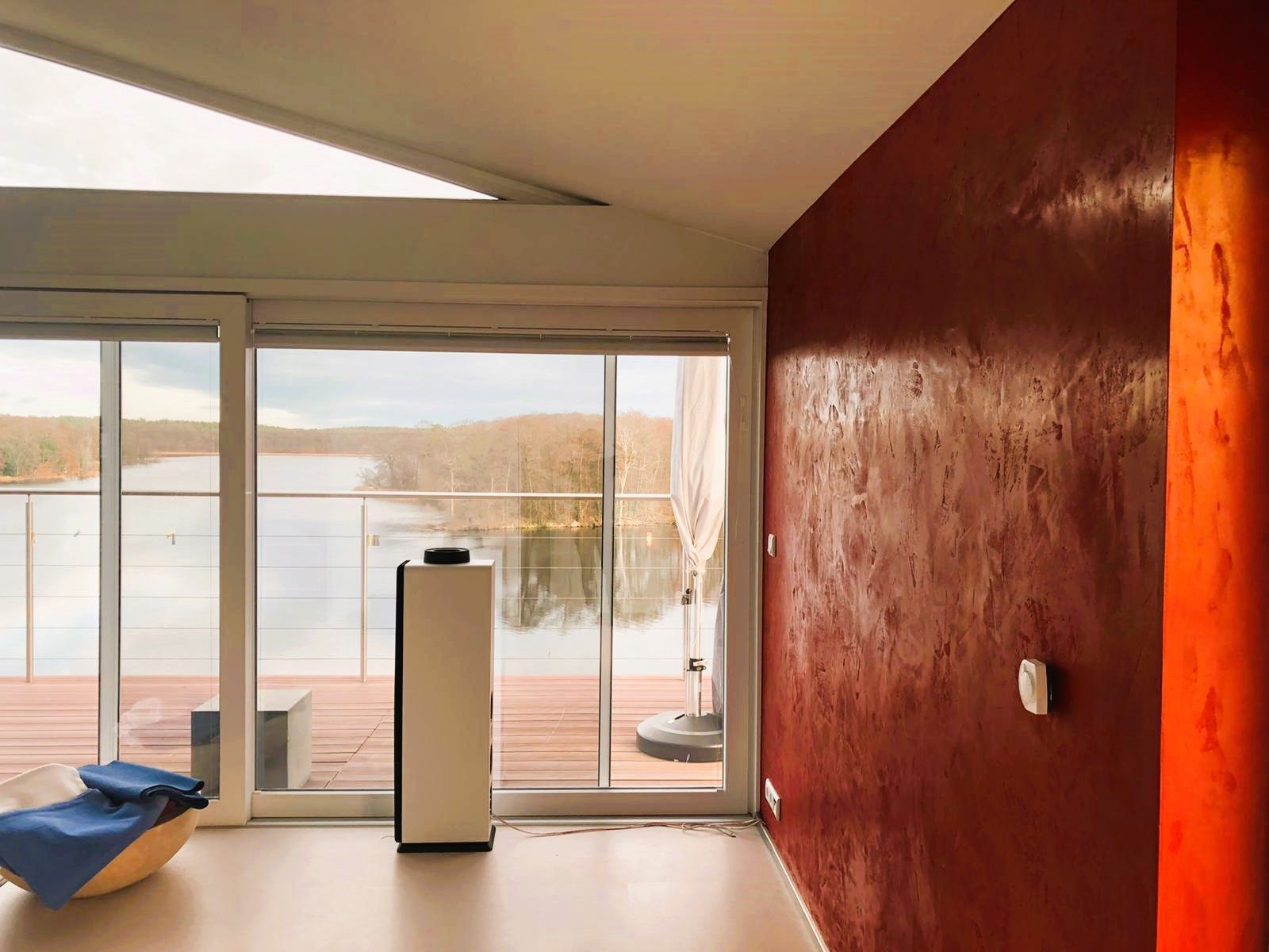 Ein Wohnzimmer mit roter Wand und Blick auf einen See