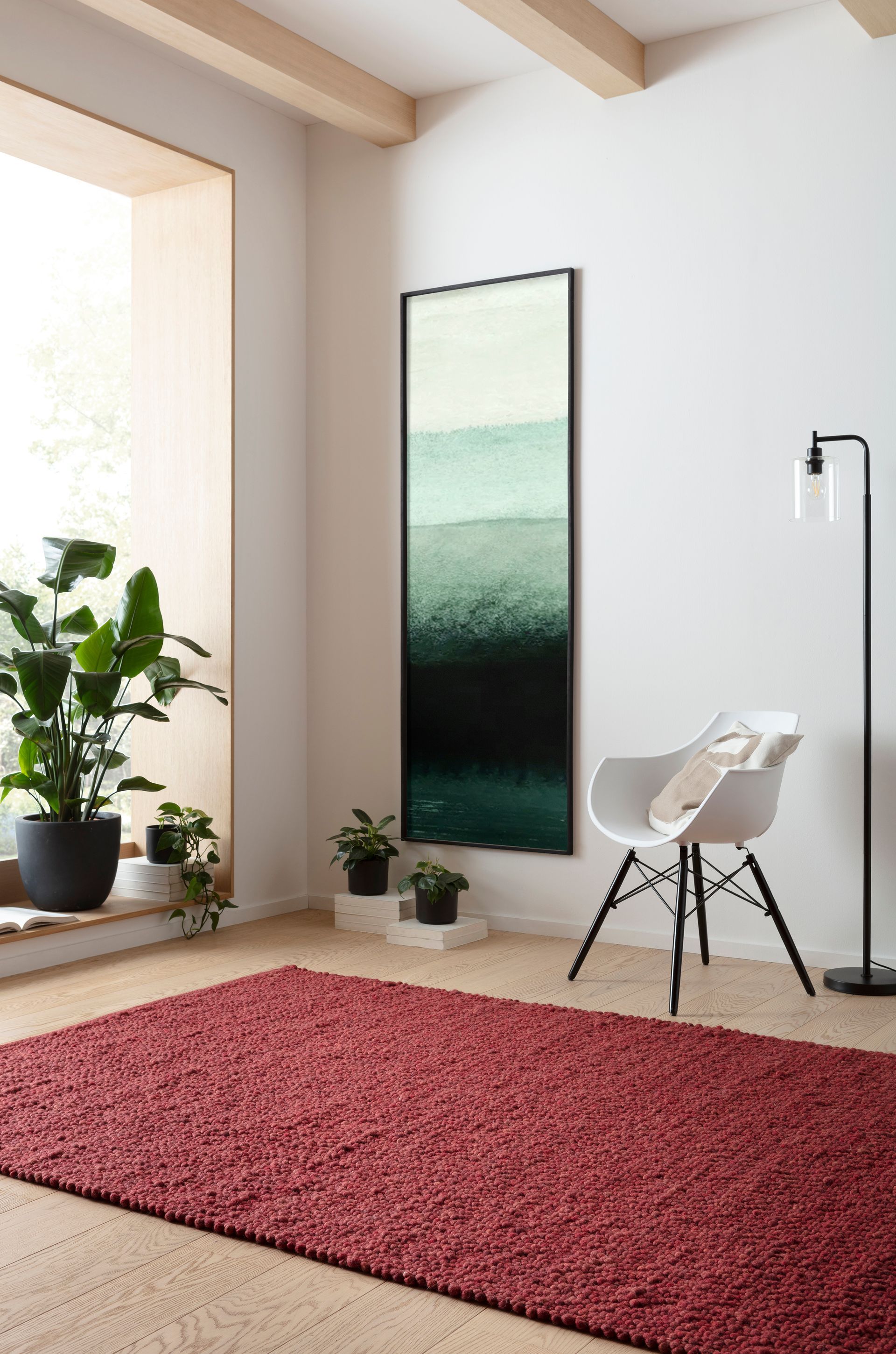 Ein Wohnzimmer mit einem roten Teppich, einem Stuhl, einer Lampe und einem Gemälde an der Wand.