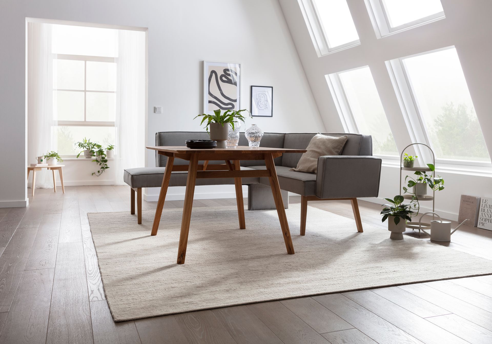Ein Wohnzimmer mit Tisch, Couch, Bank und Teppich.
