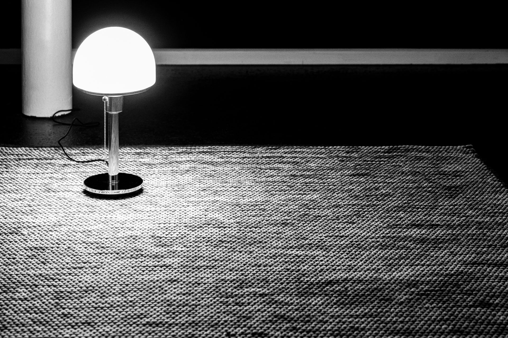 Ein Schwarzweißfoto einer Lampe auf einem Teppich.